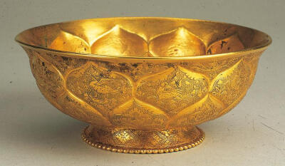 唐‖莲瓣纹弧腹金碗，采用錾刻工艺装饰出浅细的宝相花，内腹璧由内向外捶揲出浮雕大莲瓣纹，正好从多面聚拢光线到底部敛光的宝相花上，烘托出柔而不媚的整体气质。（錾刻工艺，技法起源于古人较早精通的玉、石、竹木…