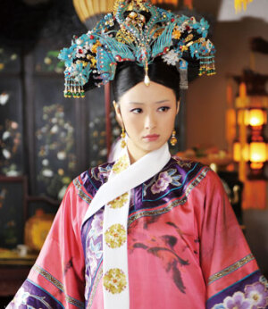 年世兰|正直盛宠的华妃，点翠凤凰旗头霸气逼人。华妃的头饰是饱满精致的点翠凤凰旗头。繁复的缕鹿髻中央是一支宝蓝凤凰镶珠鸾掐丝缀雕步摇头钗，坠着的水滴珍珠极其出彩。髻饰的亮点在于圆润莹亮的殷红镶黑红宝石，充分体现了华妃“第二凤凰”的大气怡人。赤金耳坠，脖子上的龙华是金丝绣团花图案的，比皇后娘娘的蝶舞飞花图更胜一筹，好一位风头正盛的娘娘。
