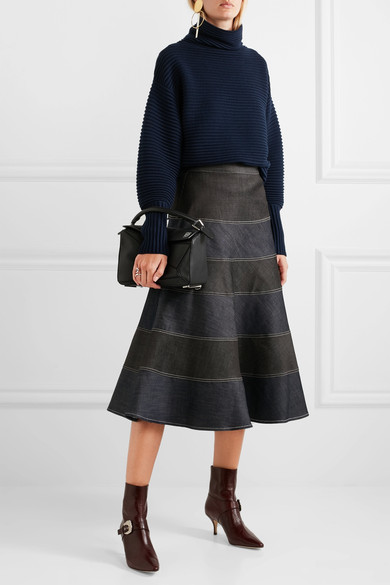 Loewe 的 “Puzzle” 包袋拥有如折纸般多变的形态，让你可有多达五种不同的方式携带——包括肩背、当为手拿包使用或旅游时完全平放于行李箱里节省空间。此一小巧版本采用黑色纹理皮革制成，白色的品牌标志图案对比鲜…