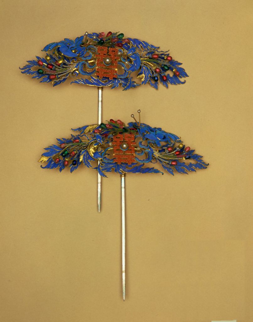 【银镀金点翠镶料石松鼠葡萄双喜头花】
清光绪，长10cm，宽5cm。清宫旧藏。
这对银质头花为清宫造办处制作。镀金点翠，以珊瑚珠及各色料石镶嵌出松鼠、葡萄、囍字纹饰，构图生动此头饰是皇后婚庆期间佩戴的。