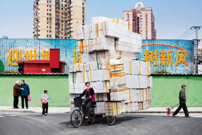 French artist Alain Delorme digitally distorts reality in his series “Totems” in which people are captured around Shanghai with precarious piles of objects.