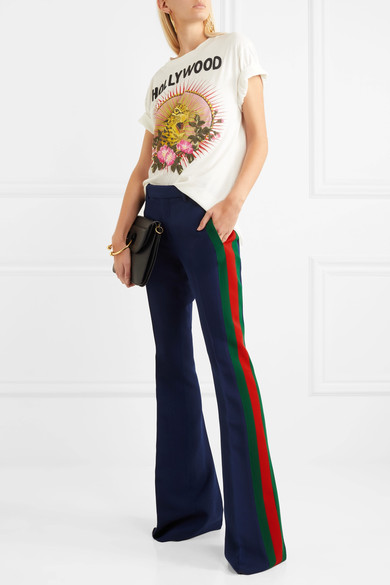 劲酷女孩们也心仪 Gucci 的精裁单品，创作歌手 SoKo 和音乐人 Rachele Bastreghi 就穿着品牌西装与长裤出席 Alessandro Michele 一手打造的新品发布秀场。这款海军蓝色喇叭裤剪裁自羊毛真丝混纺卡迪面料，侧面红绿织带条纹带出它的运动气息。标语 T 恤和运动鞋就是驾驭它的简单方式。