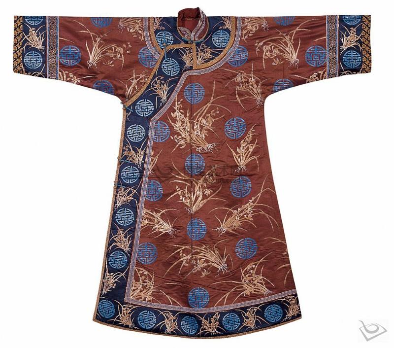 【赭色缎盘金银绣兰花万寿纹夹袍】清同治 立领、右衽、两袖平直。赭色五枚缎地上盘金银绣兰花、团寿纹，棵棵兰花都是用金银线盘钉绣制，选用的金银线是被称作“一纱金”的最细小规格的捻金、捻银线，二根并用盘钉，金银线搭配得当；在盘钉的过程中选不同的丝线搭配，就会产生不同的光色变化，色彩丰富脱俗；天青色万寿纹以直针插绣，色彩亮丽。领襟、摆、袖缘黑缎大宽边上绣同样的兰花、万寿纹。北京故宫博物院收藏的一件紫缎盘金彩绣兰花万寿纹夹袍，纹饰风格与此件极为相似。整件衣格调庄重，设计精巧，工艺高超。晚清宫庭造办处的织造工艺有所下降，但由于慈禧本人的促使，对于女服的质量而言，晚期的女服反而比中期的更为讲究。