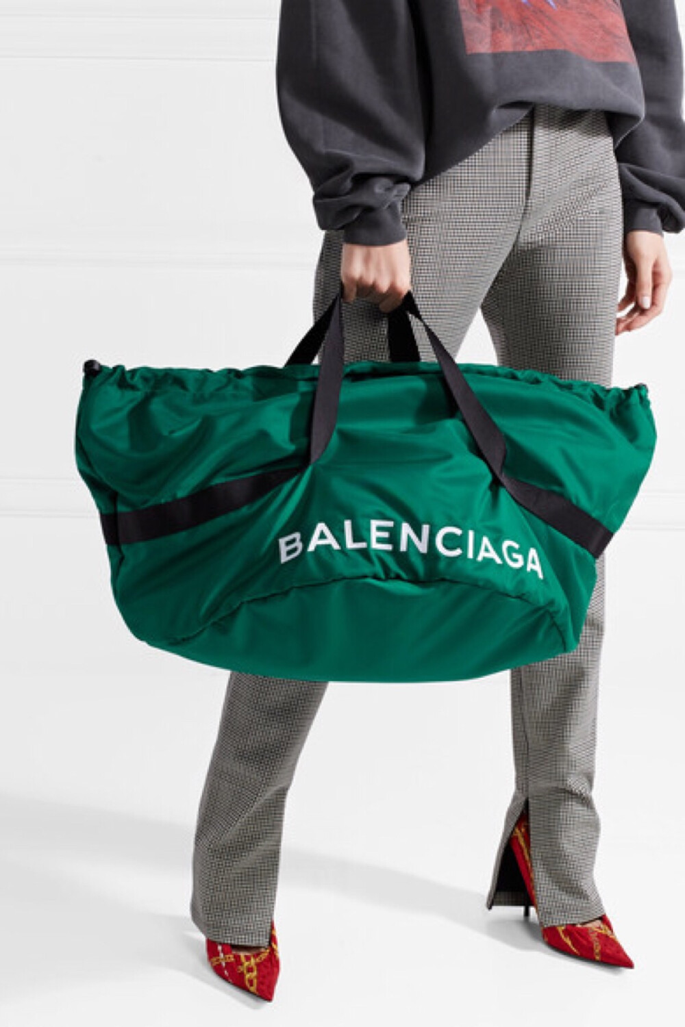 能够将实用单品打造成令人深深着迷的大热配饰，Balenciaga 绝对是这方面的专家。这款超大的 “Wheel” 包袋来自 2017 秋冬秀台系列，采用墨绿色软壳面料于意大利制成，配有黑色帆布手柄及白色的品牌标志刺绣。充裕的包身可容下你的日用品以及一双备用鞋或换洗衣服，拉链口袋则能悉心安放小物。