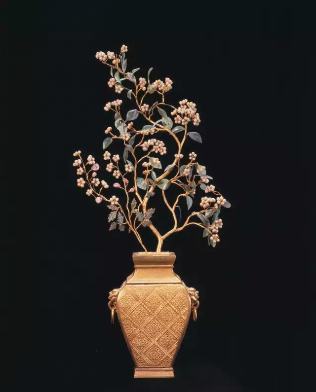 【金瓶珍珠花树景】
金瓶珍珠花树景，清，通高56.5cm，最宽27cm，瓶高20.7cm。
瓶金质，九成金。扁方形，两侧饰狮耳衔环，以錾刻的菱格纹为主体纹饰。银质内胆。瓶中插黄金树，以碧玉为叶，珍珠作花，金丝为蕊。
这种将金与珠、玉结合的工艺同北方少数民族的金器制作可能有着内在的文化传承关系。
