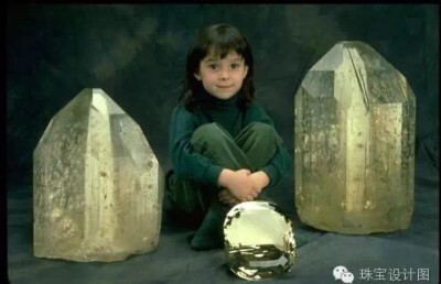 图上的托帕石是博物馆馆藏品，左右两边是未经打磨的天然原石，萌娃前方，放着那颗重达两万多克拉的、切好了的、相当干净透明的