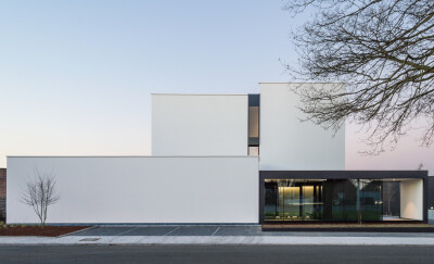 线变成面，面变成线，模糊界限的美——DELTA 住宅,© Stijn Vereeken为了与十字路口和门口的高大橡树建立联系，建筑设计采用了动态的白色垂直表面，由玻璃和对比鲜明的金属分离开来。由于项目倾斜的外形，从十字路口…