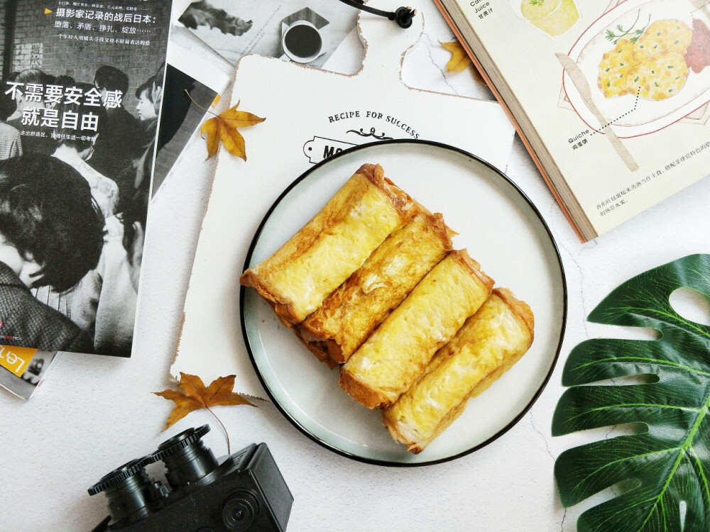 材料：吐司 黄油 芝士片 香蕉 鸡蛋 牛奶 白砂糖
做法：香蕉竖着切开，然后再从中间一刀切，也就是一根香蕉分成四份，鸡蛋只要蛋黄，打散，放入适量牛奶，白砂糖，搅拌均匀，把最终液体倒在盘子里备用，然后用擀面杖把吐司擀平，放一片芝士，再放香蕉，然后卷起来，卷口处可以刷点蛋液，防止裂开，每个吐司都这样卷好，锅里小火，放黄油，或者菜油，然后吐司卷在蛋液里滚一圈，放进锅里煎熟就好啦[奸笑]