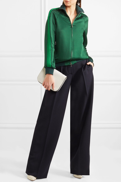 从 Valentino 这款深绿色夹克中，我们即能看到街头风格和运动潮流对品牌 2018 早春度假系列的深刻启发。单品以光泽的锤花缎布制成，罗纹领口和双袖上的浅色长条纹运动感十足。不妨参考秀场造型，搭配 配套长裤，以本…