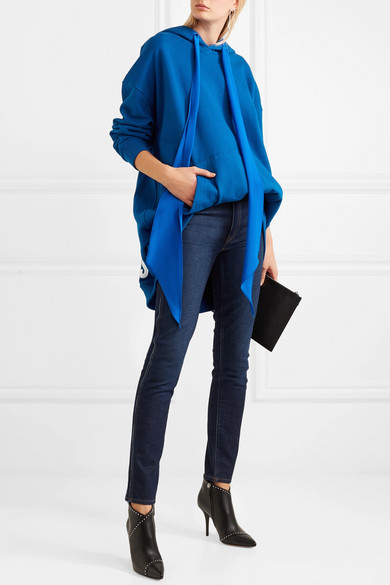 继 2017 年推出的品牌标志单品获得广泛追捧后，潮流品牌 Givenchy 这回再以趣致的手法翻新前季的设计理念。这款卫衣采用蓝色纯棉平纹针织面料裁制，兜帽上配有莹亮的真丝双绉长系带，并以品牌名称和立足城市的白色字样装点后方衣摆。不妨配以窄腿裤和利落的配饰，平衡大廓形衣身的比例。