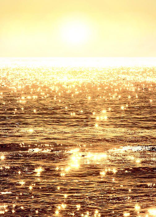 Alluring sunlight reflects upon the glassy ocean waves casting dazzling flashes of lights resembling sparkling diamonds in the sea. A photograph by artist Michael Rock