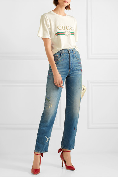 品味超群的本网站时尚总监 Lisa Aiken 曾于纽约时装周中，于风衣下配搭 Gucci 热销的 T 恤和配套长裤，将时髦造型穿出全新高度。这一新推出的大廓形版本裁自纯棉平纹针织面料，轻柔衣身正面饰有仿旧金色品牌标志和经典红绿织带，后方则以趣致的花卉贴花巧妙点缀。它的圆领经做旧处理，流露出时髦的古着韵味。