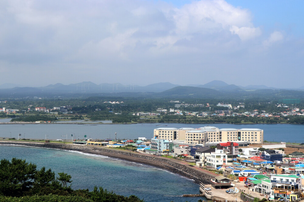  远处的蓝海泛着粼粼微光，那股海腥味似乎还若有若无地停驻在鼻尖。洁白柔软的云层像是从岛上青翠的群山生长出来，温柔地投下一片阴影。是济州啊