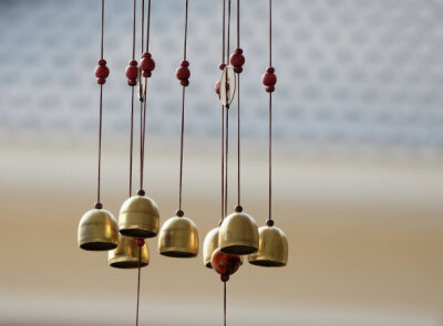 closeup brass bell mobile hanging in front of home