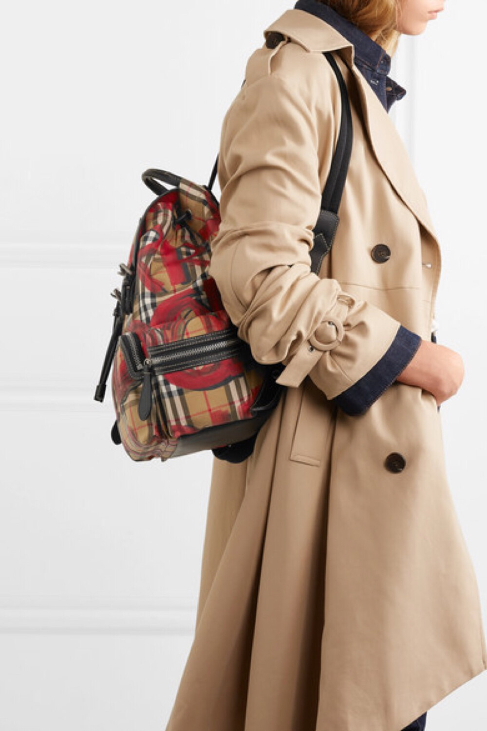 Burberry 本季为旗下的军装风双肩包披上仿旧复古格纹倪裳——其上的涂鸦印花则出自这一英伦时尚屋于伦敦盛大举行的 2018 秋冬系列。这款包袋采用与品牌经典风衣同样的华达呢面料制成，其上配有皮革边饰搭扣，并以手工漆绘的边饰勾勒包身轮廓。不妨使用可调式肩带双肩背携，或以管状手柄手提。