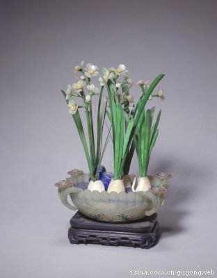 青玉菊瓣式盆水仙盆景，清中期，造办处造，通高30cm，盆径18－13cm。清宫旧藏。此盆景风格清雅，玉盆为典型的痕都斯坦风格，盆中景致牙叶挺拔，玉花明秀，反映出清代乾隆年间雕刻业盛期的工艺水平。