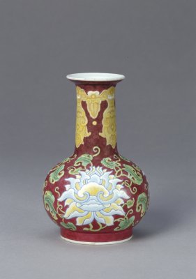 紫红地珐琅彩折枝莲纹瓶，清康熙，高13.2cm，口径4.4cm，足径5.4cm。此器是珐琅彩瓷器初创时期的一件佳作，其效果颇似铜胎画珐琅，风格朴实凝重。