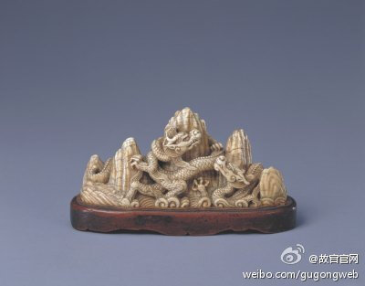 【牙雕龙纹五峰笔架】明，通座高9cm,底径16-4.5cm。此件龙纹笔架既见刀刻之功，又具雄劲风韵。雕龙蜿蜒盘曲，生动的龙身及龙须、龙嘴均显现出典型的明代风格。整座笔架雕刻得庄重浑朴，刚劲有力，属明代嘉靖、隆庆年…