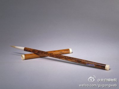 【斑竹管玉笋笔】清，通长30.7cm，径1.1cm。笔管、帽竹制。表层有褐色斑纹，故称“斑竹”。管上端阴文填蓝、绿色楷书“玉笋”。顶及帽口均镶象牙。笔头羊毫制，长锋造型。