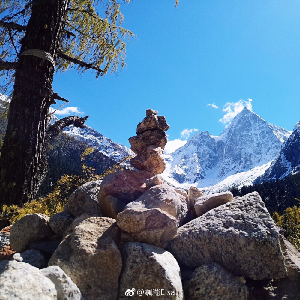 四川.阿坝州.理县.毕棚沟.磐羊湖.湖边石堆和远方的雪山.蓝天白云晴空万里.还有一丝光晕