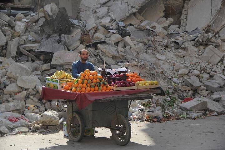 网友分享的叙利亚一个卖水果的大叔，给战乱中的废墟增添了一抹亮色，世界是灰的，可是希望还在，生活还得继续丨摄影师 ​