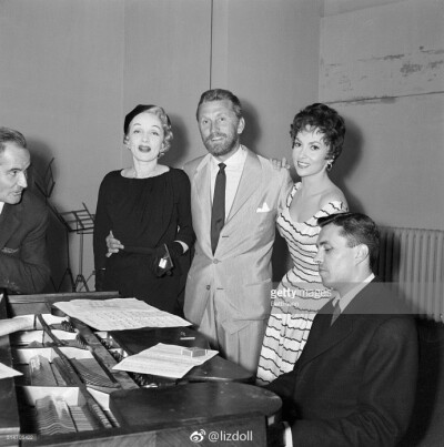 8/14/1955- Paris, France: Rehearsal time. Lovely Italian actress Gina Lollobrigida and the beautiful Marlene Dietrich (left) join a bearded Kirk Douglas in rehearsal for a song to be performed at a be…