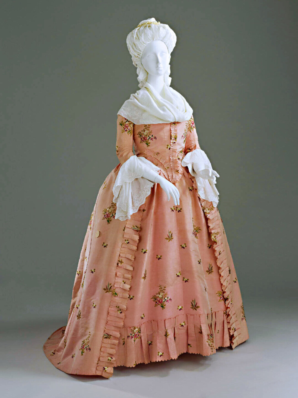 一件1770~80年代的粉红色塔夫绸碎花英式女袍。这种田园风的裙子很得玛丽·安托瓦内特喜爱，并被大力推广。虽然较之以前的流行款，它看上去简洁得多，但有趣的是并不便宜，因为上面这些海量的小清新花纹全部都是手工绣出来的！所以当时玛丽王后订购的小花裙也是一笔巨额开支。 ​​​
