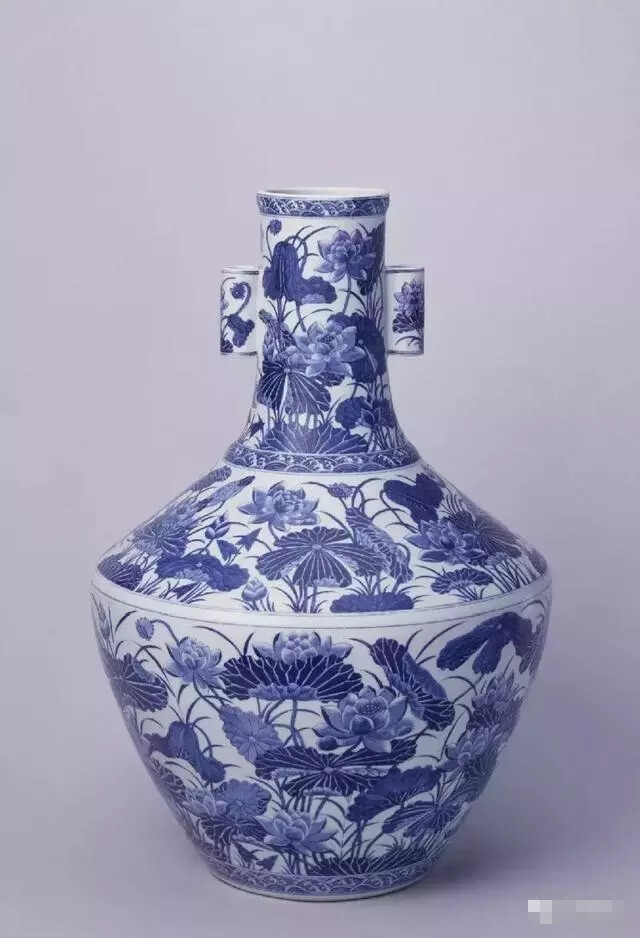 “清”乾隆 青花荷蓮紋貫耳瓶
高55cm，口徑11cm，足徑18cm
瓶口微撇，長(zhǎng)頸，折肩，弧腹下斂，圈足。頸兩側(cè)對(duì)稱置貫耳。通體青花裝飾。頸、肩、腹部均繪荷蓮紋，輔以海水紋邊飾。圈足內(nèi)施白釉。外底署青花篆體“大清乾隆年制”六字三行款。
此瓶造型為乾隆時(shí)新創(chuàng)，引人注目的是其肩部設(shè)計(jì)較寬，使器物平添了幾分穩(wěn)重感。所繪荷蓮紋筆觸細(xì)膩，婀娜多姿，而且使用濃淡不同的料水表現(xiàn)物象的陰陽(yáng)向背，物象顯得更加生動(dòng)逼真。其畫稿必定出自當(dāng)時(shí)具有極高藝術(shù)修養(yǎng)的宮廷畫家之手。