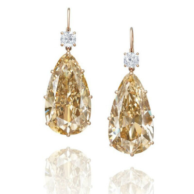 AN EXCLUSIVE PAIR OF COLOURED DIAMOND AND DIAMOND EAR PENDANTS Each suspending a pear-shaped fancy brownish yellow diamond weighing approximately 28.65 and 28.27 carats, surmounted by a cushion-shaped…