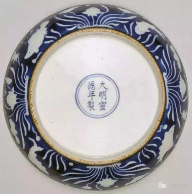 “明”宣德 霁蓝釉白花鱼莲纹盘
高4cm，口径19.2cm，足径12.7cm
此盘器型规整，胎体厚重，蓝釉厚润莹亮。盘敞口，弧壁，圈足。内外均以宝石蓝釉为地，并饰白釉鱼莲纹装饰。
盘心在白色圈栏内绘莲池游鱼图，两尾游鱼潜游于漂浮的水草与盛开的莲花之间，外壁亦绘莲池游鱼纹，荷莲与游鱼规则地相间排列。
足内施白釉，青花双圈内楷书“大明宣德年制”六字款。