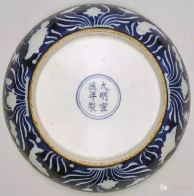 “明”宣德 霁蓝釉白花鱼莲纹盘
高4cm，口径19.2cm，足径12.7cm
此盘器型规整，胎体厚重，蓝釉厚润莹亮。盘敞口，弧壁，圈足。内外均以宝石蓝釉为地，并饰白釉鱼莲纹装饰。
盘心在白色圈栏内绘莲池游鱼图，两尾…