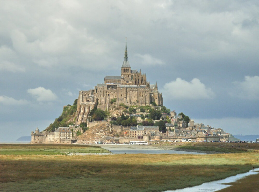 【法国·世界各国建筑】圣米歇尔山（Mont st Michel）位于法国诺曼底和布列塔尼之间，历史可追溯到公元708年。当年红衣主教奥贝梦见守卫天堂入口的大天使米歇尔手指墓石山，示意他在此修建教堂。之后的800年间，无数教士和劳工将一块块沉重的花冈岩运过流沙，一步步拉上山顶。到16世纪，圣米歇尔山教堂群才真正完工——奥贝的一场梦让人整整忙活了8个世纪。