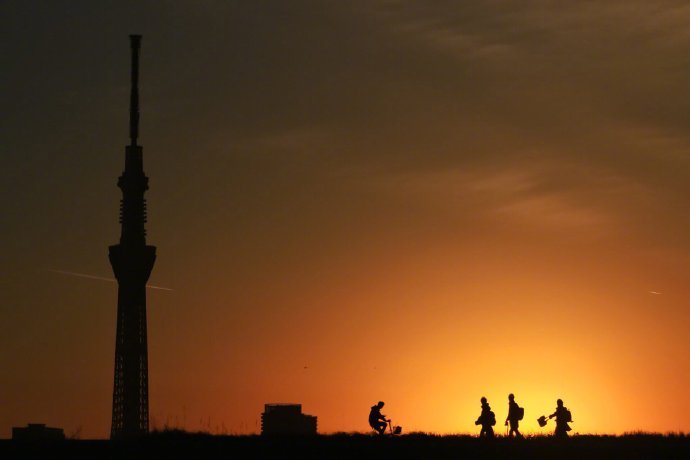 一位推主拍夕阳下的东京天空树，刚好遇到几个女学生从河堤上走过，还注意到了他的镜头，即兴摆起pose来...突然觉得青春真美好，生活真美好