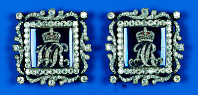 King William IV&Queen Adelaide Enamel Buckles 这两块方形蓝色珐琅扣最初属于威廉四世的妻子阿德莱德王后，被钻石设计包围着的蓝色珐琅扣中心分别用钻石镶嵌了代表他们夫妇二人名号的缩写“WR”和“AR”，1849年…