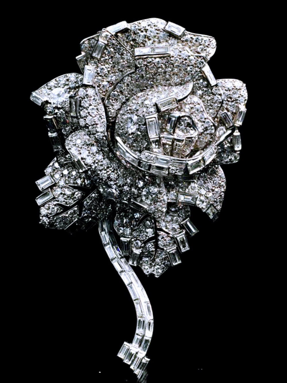 Princess Margaret's Cartier Diamond Rose Brooch 这枚玫瑰型的钻石胸针是卡地亚珠宝在1938年制作完成的，高7cm，镶嵌有长方形、单颗和圆形切割钻石，造型就是一朵盛开的玫瑰花。最早见玛格丽特公主佩戴是在1953年6月女王的加冕典礼上，最大的可能性就是当时谁送给她的礼物来着，那之后一直到60年代中期这枚胸针的出镜率都特别高，各类场合大小宴会招待会都能见到佩戴，上世纪60年代末以后就不太能见到了，直到90年代初才被公主重新翻出来戴。2002年玛格丽特去世后由她的子女继承，四年后胸针在佳士得拍卖行拍卖，成交价153,600英镑，胸针目前已经被卡地亚回购，在他们近年举办的主题展览上可以看得到。