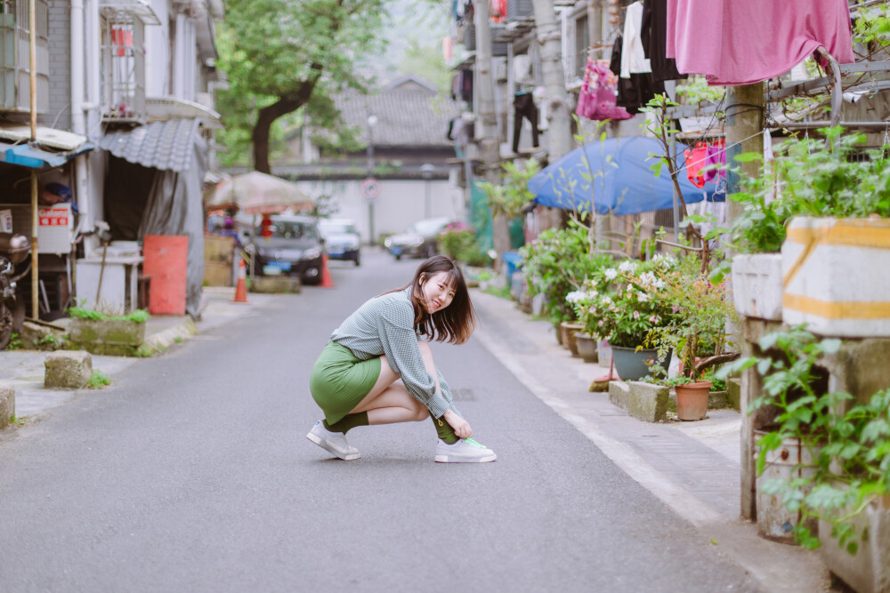 牛油果小姐
摄影：洪小漩
出镜：若男
场地：馒头山社区
馒头山社区在杭州摄影圈子里，那是有一定地位的。
在这里，有一颗杭州市斤的老灵魂。
在G20之前，馒头山社区应该还要多几分破败，不过，后来被修缮了一番。修缮后的模样，在我看来，仿佛是个老态龙钟的前辈，换了件相对体面的外套。
虽然我不知道社区居民对于修葺一新后的家如何思量，但是我依然喜欢走进些，再走进些，探访那些斑驳的民居，听听门前屋后的老杭州不紧不慢地聊着天。
若男那天穿得像一颗活泼的牛油果，素来极具亲和力的她瞬间和社区阿姨养的一条泰迪熟络起来。
泰迪叫贝贝，阿姨说，贝贝通体雪白，可是个白雪公主呢。只要有来着拍照的小年轻，大家总喜欢把贝贝逗上一逗。我们家贝贝呀可是馒头山的网红呢，是吧，阿姨把眼皮从手上忙活不停的针线活中抬了抬，看了看贝贝，如是说道。
生活在这里，应该也很有趣吧。