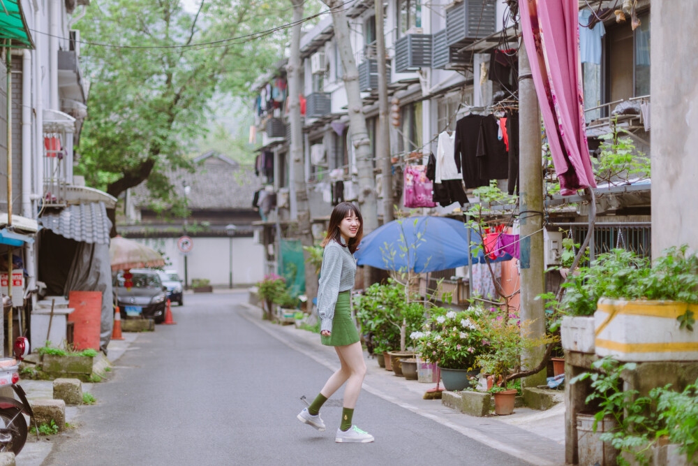 牛油果小姐
摄影：洪小漩
出镜：若男
场地：馒头山社区
馒头山社区在杭州摄影圈子里，那是有一定地位的。
在这里，有一颗杭州市斤的老灵魂。
在G20之前，馒头山社区应该还要多几分破败，不过，后来被修缮了一番。修缮后的模样，在我看来，仿佛是个老态龙钟的前辈，换了件相对体面的外套。
虽然我不知道社区居民对于修葺一新后的家如何思量，但是我依然喜欢走进些，再走进些，探访那些斑驳的民居，听听门前屋后的老杭州不紧不慢地聊着天。
若男那天穿得像一颗活泼的牛油果，素来极具亲和力的她瞬间和社区阿姨养的一条泰迪熟络起来。
泰迪叫贝贝，阿姨说，贝贝通体雪白，可是个白雪公主呢。只要有来着拍照的小年轻，大家总喜欢把贝贝逗上一逗。我们家贝贝呀可是馒头山的网红呢，是吧，阿姨把眼皮从手上忙活不停的针线活中抬了抬，看了看贝贝，如是说道。
生活在这里，应该也很有趣吧。