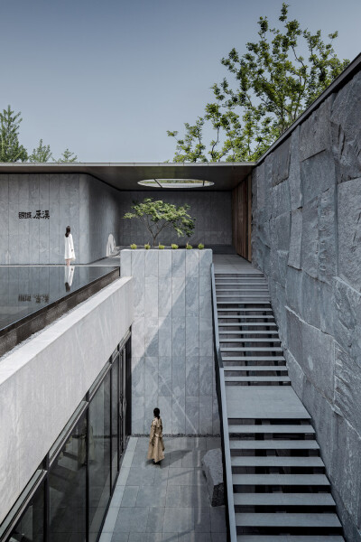 连接上下层庭院的山石墙和漂浮的台阶，seemingly floating staircase connects upper and lower courtyards by the stonewall