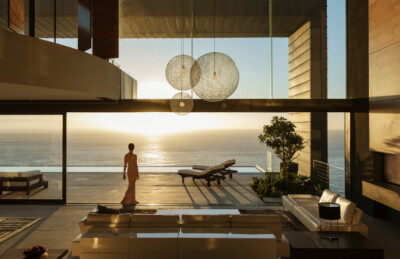 太阳,人,住宅内部,沙发,建筑_478169445_Woman in modern house overlooking ocean_创意图片_Getty Images China