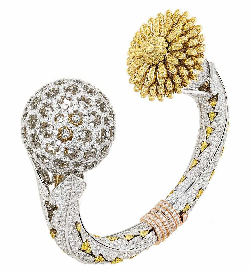 Van Cleef & Arpels「Dandelion Secret」
这枚手镯式珠宝表以「蒲公英」为设计灵感，表镯勾勒出弧形的叶茎轮廓，两端分别延伸为蒲公英的种子和花朵——种子是一颗立体镂空的白金小球，钻石装点让人联想起纯白的羽絮，透过小球还能隐约看到纤细的金质花葶，佩戴时钻石会摇曳闪烁；花朵则由明亮的黄钻铺陈，通过双层结构将表盘自然隐藏。