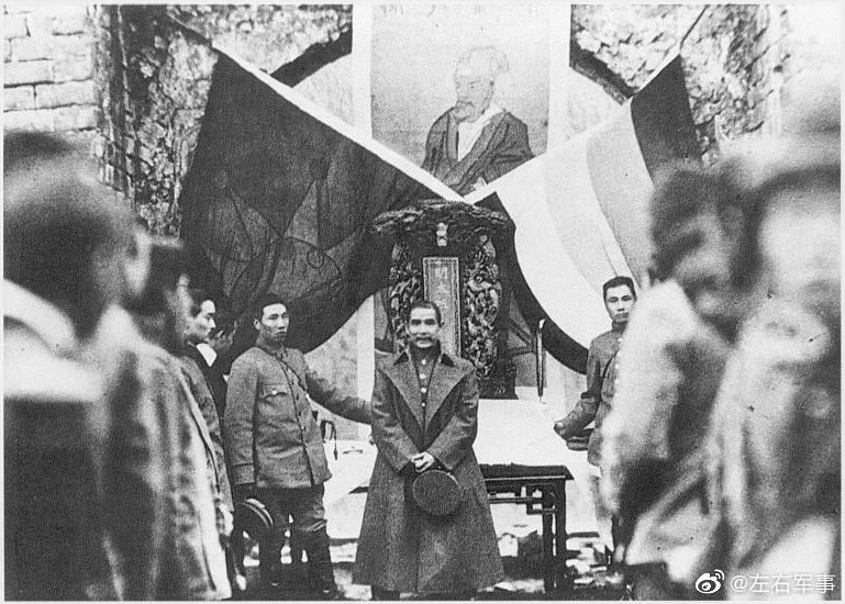 1912年2月15日，孙文祭明孝陵时向文武百官讲话。图内后方挂有明太祖像，像下放有明太祖牌位，两旁摆放着五色旗及十八星旗。