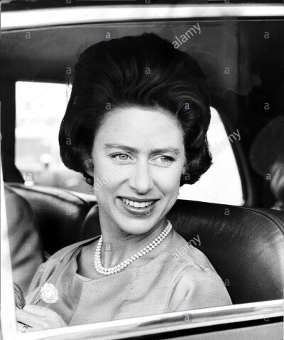 Princess Margaret in 1963 smiles while holding a flower after returning from a holiday in Greece with Lord Snowdon ​​​