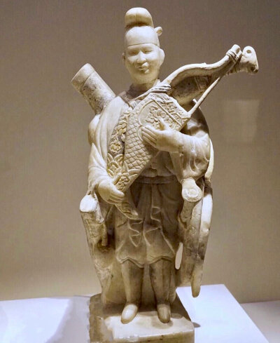 唐描金石刻武士俑，1958年西安杨思勖墓出土。典型唐代男子幞头和圆领袍衫，气宇轩昂，立于方座。全身披挂弯刀、弓、剑等两套战具。杨思勖为宦官，跟随玄宗平定叛乱，被封为骠骑大将军。性情凶狠，对待俘虏十分残忍“…