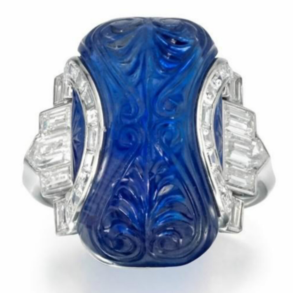  蓝宝石戒指，1925年，主石为一颗雕花蓝宝石，产自缅甸抹谷，在印度进行雕刻，主石周围点缀钻石，戒托由铂金制作。纽约欧洲艺术博览会（TEFAF）