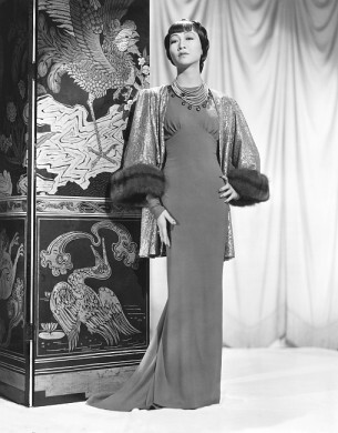 Anna May Wong in an Edith Head-designed crepe dinner gown with a jacket of emerald, green and gold lame trimmed with sable, Paramount portrait, 1937