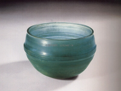 玻璃弦纹杯（西汉）
高：5.5cm
口径：7.3cm
底径：4cm
收藏： 1987年广西合浦县文昌塔70号墓出土 广西壮族自治区博物馆藏。
此杯呈浅蓝色，敛口，弧腹，自腹下内收，小平底，底心略内凹。腹部饰细弦纹3道。该杯保…