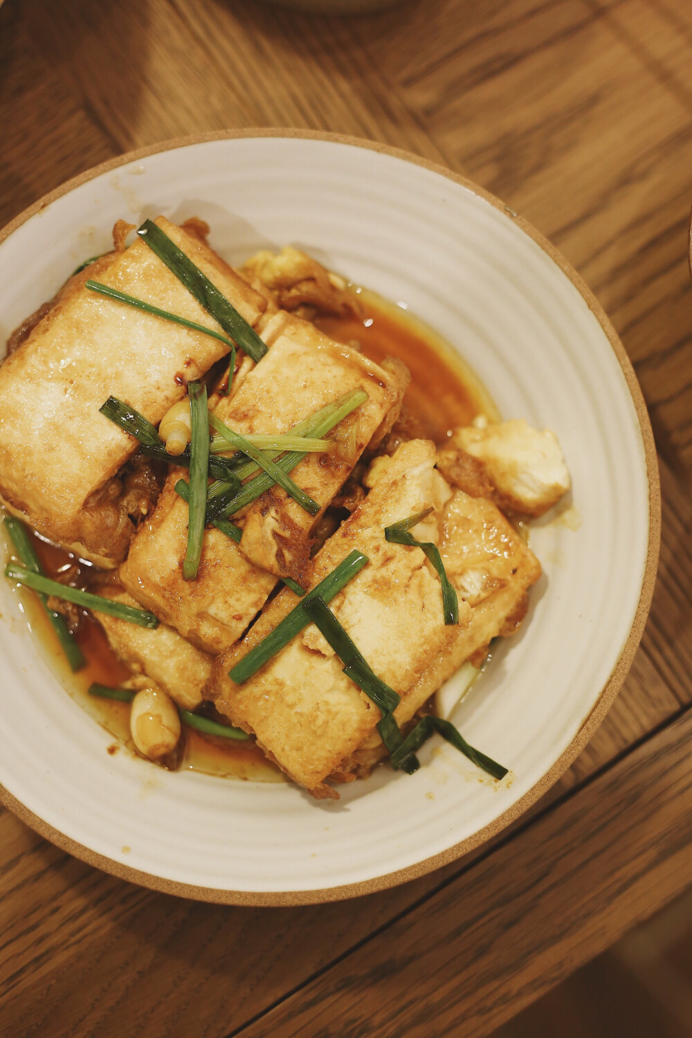 虾仁煨豆腐，两分钟出锅的好味快手家常。
食材：嫩豆腐一块，鲜虾几只。
做法很简单：嫩豆腐泡过盐水，稍稍去除豆腥味。对切再等分为三片。
1、平底锅内加入底油，轻轻取豆腐块蘸上鸡蛋液入锅煎
（tips：害怕溅油的话，入锅的时候可以关小火，之后再转大火）
2、大约一分钟，表面成型后翻面，同时加入虾仁。
3、准备调汁，老酒3汤匙，生抽1汤匙，白糖少许，口重的话可以再加少许盐。
4、出锅前撒一点葱段即成
快手、下饭、营养丰富，趁着周末在家试试哟！