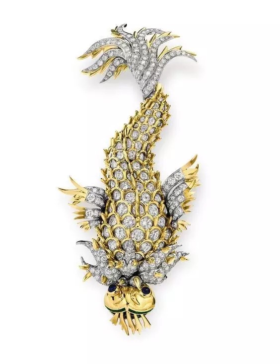 这枚海豚造型的胸针全身设计为18K黄金抛光的圆形切割钻石，带有密钉镶钻石以及圆形蓝宝石和切割翡翠点缀/Tiffany & Co