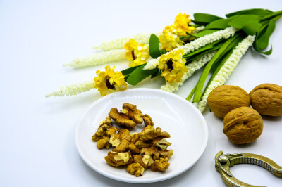 食品 食物 植物 果实 成熟的 特写 绿色食品 美味 零食 坚果 干果 核桃 核桃仁 膳食纤维 小吃 益智 亚洲 健康食物 有机食品 膳食 养生 滋补 营养 食材 生活方式 健康的 白色背景 白瓷盘 干果钳 简单背景
