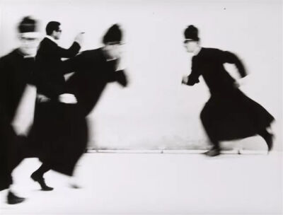 第二位摄影师是Mario Giacomelli，他以极强的对比度使照片呈现出最纯粹的黑与白。图像中的人物的神情被缩小，而以动作作为抒情的语言，仿佛跃然于纸上的文字。